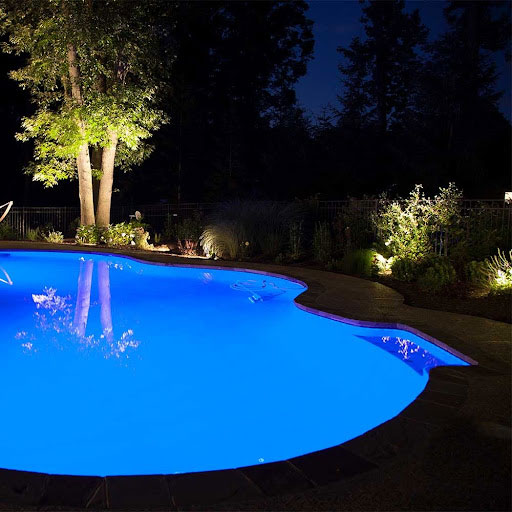 in-ground pool with lighting around it at night