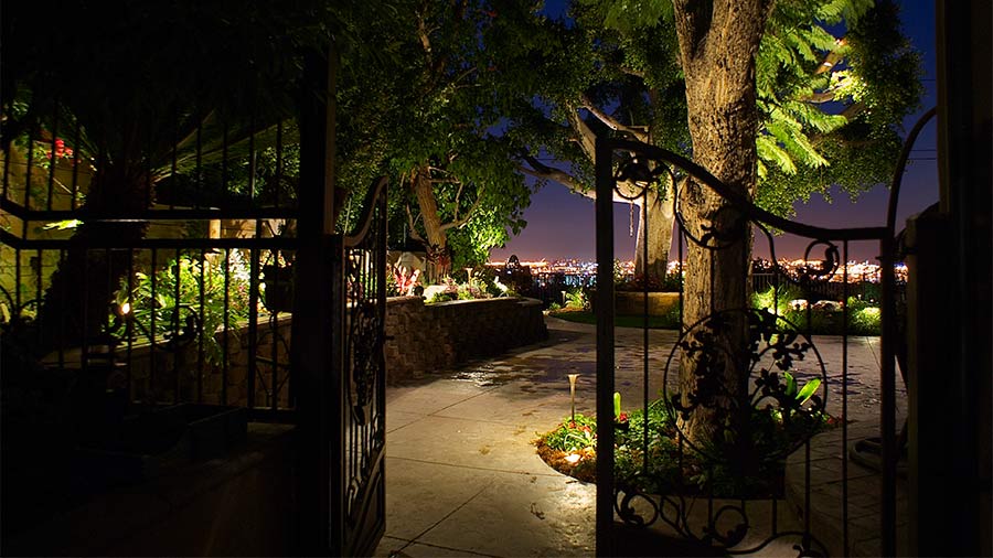 View through a gate to a restaurant's outdoor dining location at night.