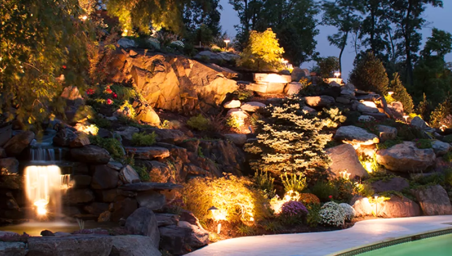 rocks-in-back-yard-by-pool-at-night-with-lights