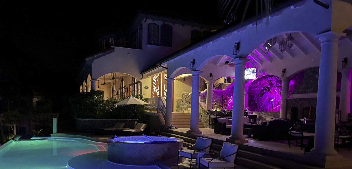 patio-illuminated-with-purple-light-at-night-next-to-pool