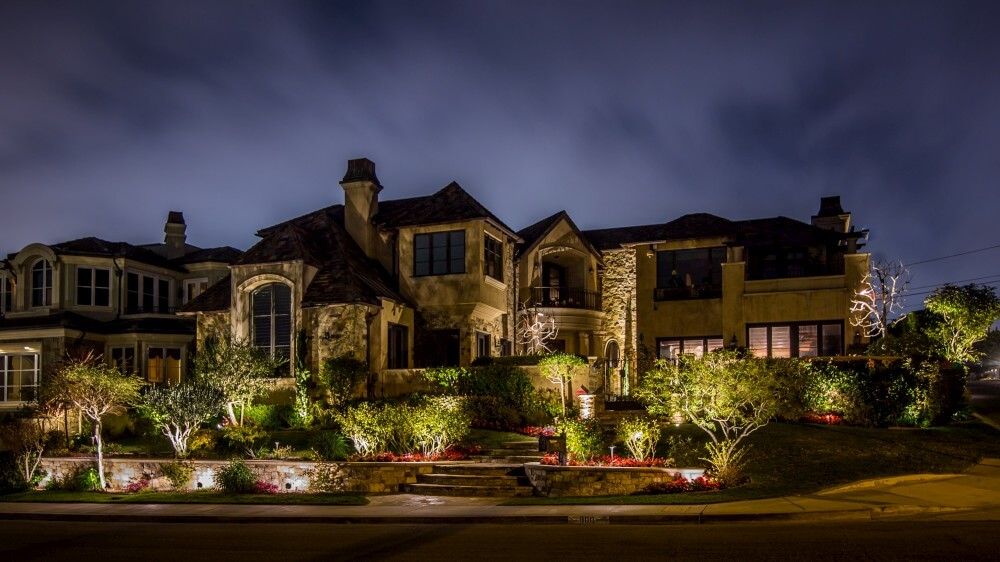 luxury home with landscape lighting highlighting the yard and exterior of the home